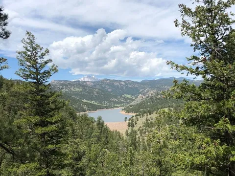 Button Rock reservoir seen through ponderosa pines from the dam trail, snow on the high peaks along the skyline